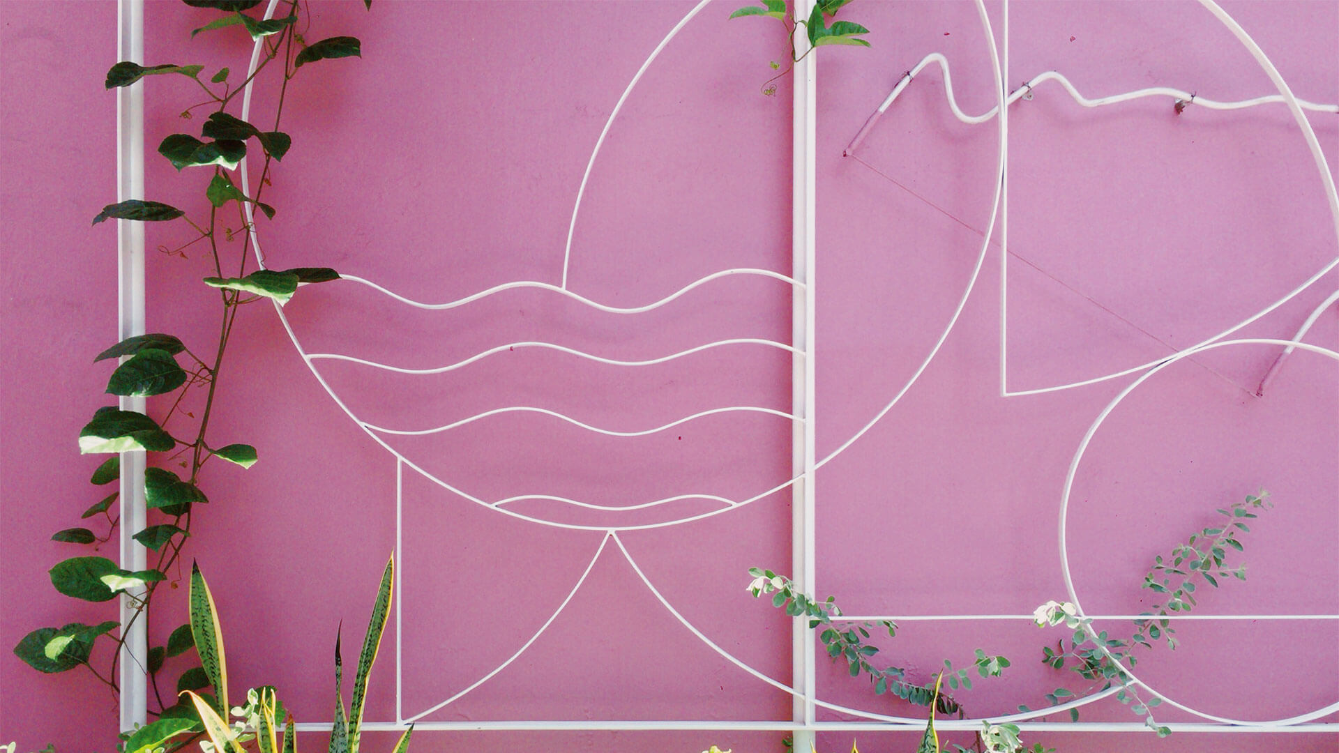 Abstract metal designs on a bright pink wall at KL Journal Hotel